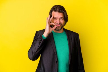 Sarı arka planda izole edilmiş orta yaşlı beyaz bir adam parmakları dudaklarında bir sır saklıyor..
