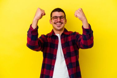 Sarı arka planda izole edilmiş, tasasız ve heyecanlı genç beyaz bir adam. Zafer konsepti.