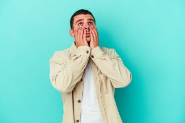 Kafkasyalı genç adam mavi arka planda izole edilmiş sızlanıyor ve ağlıyordu..