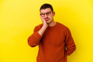 Sarı arka planda izole edilmiş genç beyaz adam yorgun ve uykulu ellerini başının üstünde tutuyor..