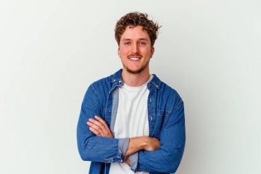 Beyaz arka planda kendini güvende hisseden, kararlılıkla kollarını kavuşturan beyaz tenli genç bir adam..