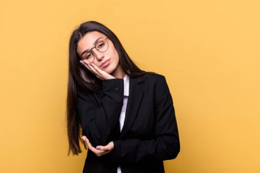 Sarı arka planda izole edilmiş genç Hintli iş kadını. Sıkılmış, yorgun ve dinlenmeye ihtiyacı var..