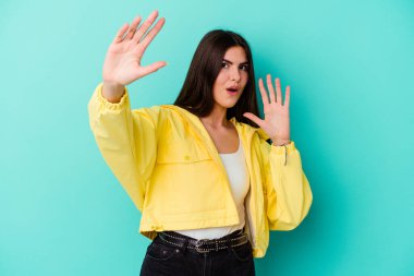 Genç beyaz kadın, mavi arka planda izole edilmiş. Yakın bir tehlike nedeniyle şoka uğruyor.