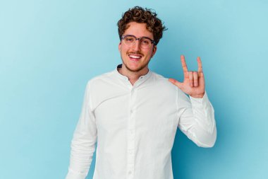 Kafkasyalı genç iş adamı mavi arka planda izole edilmiş boynuzları bir devrim konsepti olarak gösteriyor..