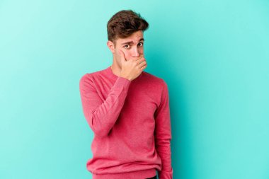 Kafkasyalı genç adam mavi arka planda izole edilmiş korkmuş ve korkmuş..
