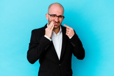 Genç, beyaz, kel bir adam mavi arka planda izole edilmiş, güçlü bir diş ağrısı, azıdişi ağrısı var..