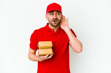 Beyaz arka planda izole edilmiş beyaz tenli teslimatçı bir dedikoduyu dinlemeye çalışıyor..