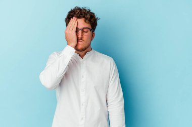Kafkasyalı genç iş adamı mavi arka planda izole edilmiş bir şekilde bir şeyi unutuyor. Alnına avuç içi ve kapalı gözlerle vuruyor..
