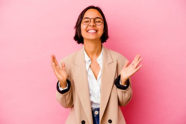 Pembe arka planda izole edilmiş genç iş kadını elini göğsünde tutarak kahkahalar atıyor..