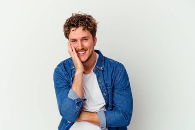 Beyaz arka planda izole genç beyaz adam mutlu bir şekilde gülüyor ve ellerini karnının üstünde tutarak eğleniyor..