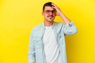 Sarı arka planda izole edilmiş genç beyaz adam bir şeyi unutuyor. Alnına avuç içi ve kapalı gözlerle vuruyor..