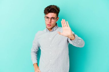 Mavi arka planda izole genç beyaz adam yakın bir tehlike nedeniyle şoka uğruyor