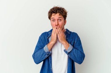 Beyaz arka planda izole edilmiş genç beyaz adam elleriyle ağzını kapatırken şok oldu..