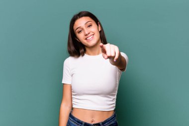 Genç Hintli kadın mavi arka planda soyutlanmış neşeli gülümsemeler ön tarafı işaret ediyor.