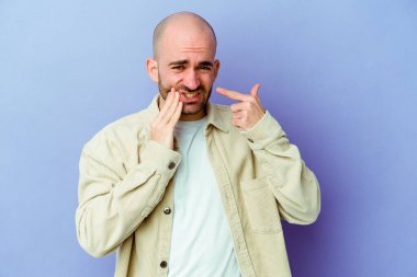 Kafkasyalı kel adam mor arka planda izole edilmiş güçlü bir diş ağrısı, azıdişi ağrısı var..