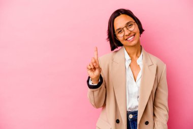 Pembe arka planda izole edilmiş genç iş kadını parmaklarıyla bir numarayı gösteriyor..