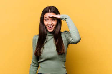 Sarı arka planda izole edilmiş genç Hintli kadın yüksek sesle bağırıyor, gözlerini açık ve ellerini gergin tutuyor..