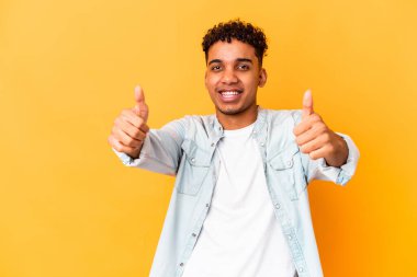 Genç Afro-Amerikalı kıvırcık adam mor renkte izole edilmiş gülümsüyor ve başparmağını kaldırıyor.