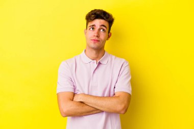 Sarı arka planda izole edilmiş genç beyaz adam hedeflere ve amaçlara ulaşma hayali kuruyor.