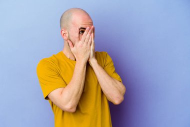 Mor arka planda izole edilmiş beyaz kel bir adam parmaklarıyla gözünü kırp korkmuş ve gergin..