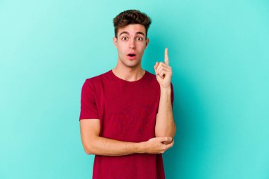 Kafkasyalı genç adam mavi arka planda izole edildi. Harika bir fikri var, yaratıcılık kavramı..