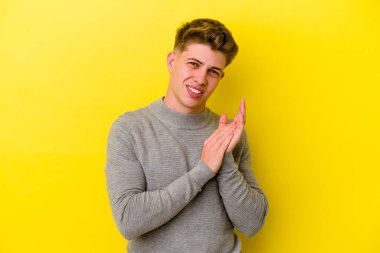 Sarı arka planda izole edilmiş genç beyaz adam enerjik ve rahat hissediyor, ellerini ovuşturuyor kendinden emin..