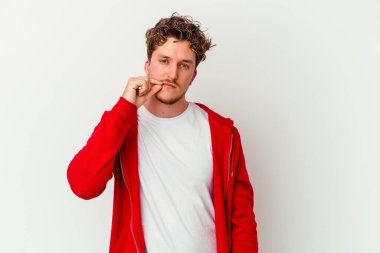 Beyaz arka planda izole edilmiş beyaz tenli genç bir adam parmakları dudaklarında bir sır saklıyor..