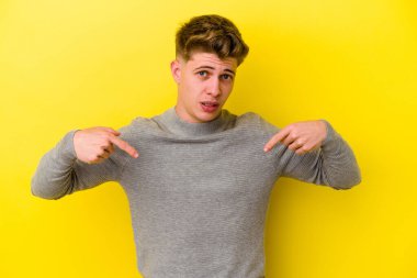 Sarı arka planda izole edilmiş genç beyaz adam parmakları aşağıda, olumlu bir his var..