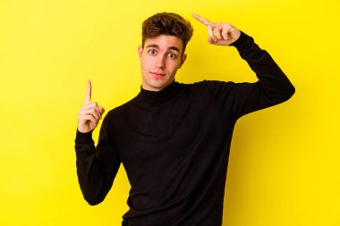 Genç beyaz adam sarı arka planda izole edilmiş ve elinde bir ürün var..