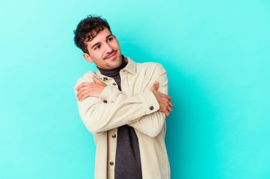 Kafkasyalı genç adam mavi arka planda izole edilmiş, güler yüzlü ve mutlu..