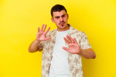 Sarı arka planda izole edilmiş beyaz bir adam iğrenme hareketi gösteren birini reddediyor..