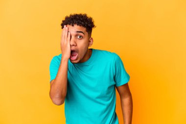 Genç Afro-Amerikan kıvırcık adamı, mor renkte izole edilmiş, yüzünün yarısını palmiye ile kaplayarak eğleniyor..