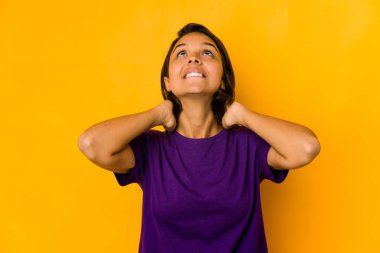 Genç İspanyol kadın sarıda izole edilmiş, kendinden emin, elleri başının arkasında..