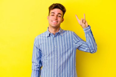 Sarı arka planda izole edilmiş genç beyaz adam boynuzlarını devrim konsepti olarak gösteriyor..