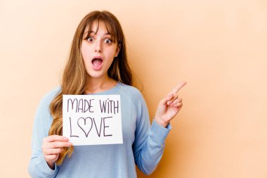 Kafkasyalı genç bir kadın aşk levhası taşıyor. Yan tarafı işaret ediyor.