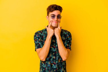 Hawaii gömleği giyen, sarı arka planda izole edilmiş beyaz bir adam iki seçenek arasında kuşkulanıyor..