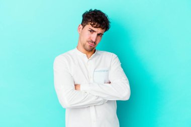 Mavi arka planda izole edilmiş genç beyaz adamın yanakları şişer, yorgun bir ifadesi vardır. Yüz ifadesi kavramı.