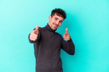 Mavi arka planda izole edilmiş genç beyaz adam öne bakan neşeli gülümsemeler.