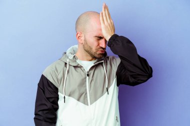 Kafkasyalı kel adam mor arka planda izole edilmiş bir şekilde bir şeyi unutuyor. Alnına avuç içi ve gözlerini kapayarak vuruyor..