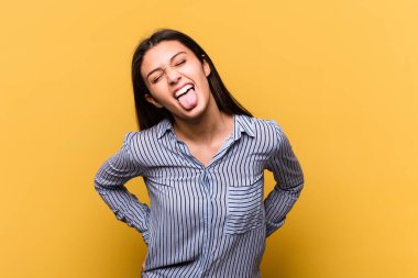 Sarı arka planda izole edilmiş genç bir Hintli kadın. Komik ve dost canlısı bir dil uzatıyor..