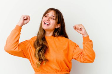 Beyaz arka planda izole genç beyaz kadın özel bir günü kutluyor, atlıyor ve enerjiyle kollarını kaldırıyor..