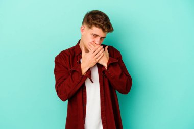 Kafkasyalı genç adam mavi arka planda izole edilmiş ağzı kapalı ve elleri endişeli görünüyor..