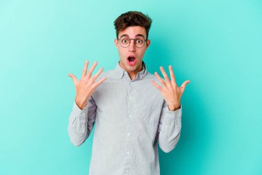 Mavi arka planda izole edilmiş genç beyaz adam on numarayı elleriyle gösteriyor..