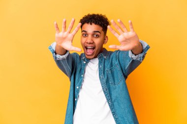 Genç Afro-Amerikalı kıvırcık adam mor üzerine izole edilmiş. Elleriyle on numarayı gösteriyor..