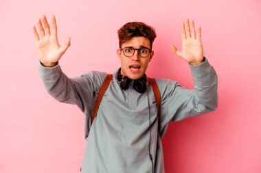 Pembe arka planda izole genç bir öğrenci yakın bir tehlike nedeniyle şoka uğruyor.