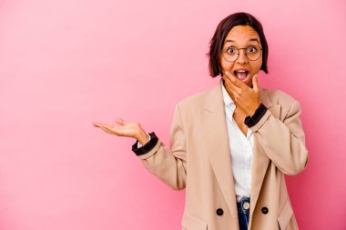 Pembe arka planda izole edilmiş genç iş kadını bir avuç içinde fotokopi alanı tutuyor, el üstünde tutuyor. Şaşırmış ve mutlu..