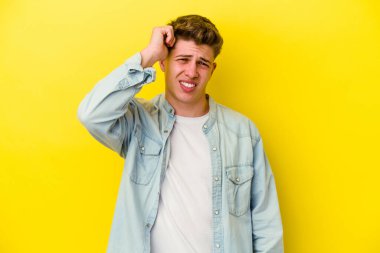 Sarı arka planda izole edilmiş genç beyaz bir adam bir şeyi unutuyor. Alnına avuç içi ve gözlerini kapayarak vuruyor..