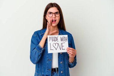 Beyaz arka planda izole edilmiş aşk levhasını tutan beyaz bir kadın kafasının arkasına dokunuyor, düşünüyor ve bir seçim yapıyor..