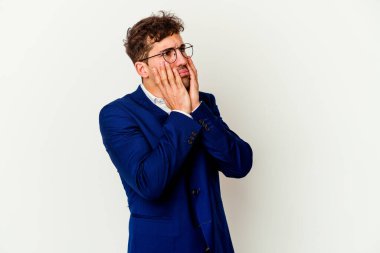 Beyaz arka planda beyaz tenli, ağlayan ve sızlanan genç bir beyaz adam var..