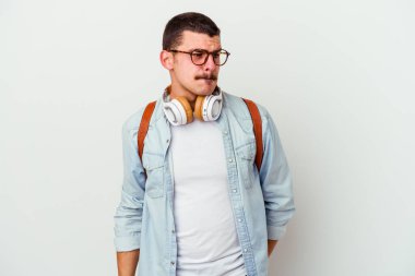 Beyaz arka planda izole edilmiş müzik dinleyen genç beyaz bir öğrenci kafası karışmış ve kendinden emin değil..